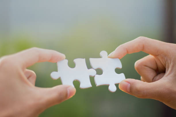 istock Two human hands connected jigsaw puzzle white, Joint Business Concepts. 999706376