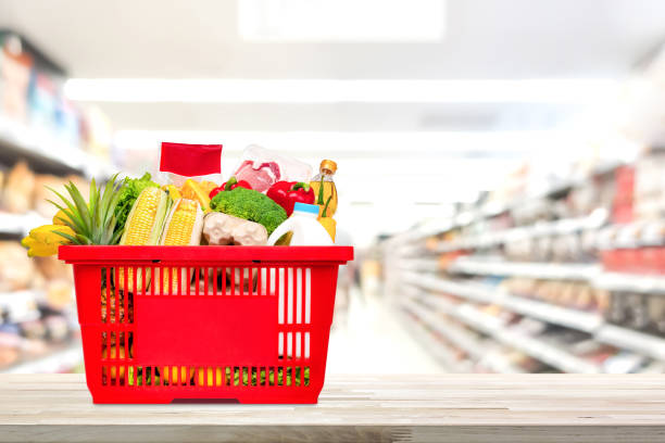 shopping basket full of food and groceries on the table in supermarket - shopping basket imagens e fotografias de stock