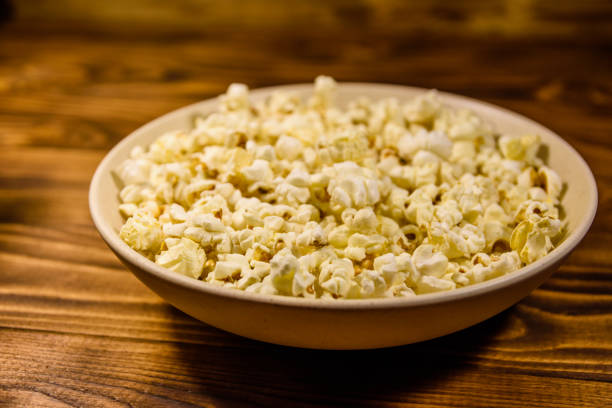 istock Ceramic plate with popcorn on wooden table 999763104
