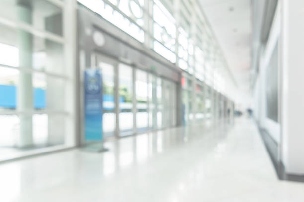 istock Office business building blur background of white empty room inside lobby hall interior, medical clinic hallway, or airport terminal corridor passage way with blurry light from glass wall window 999763926