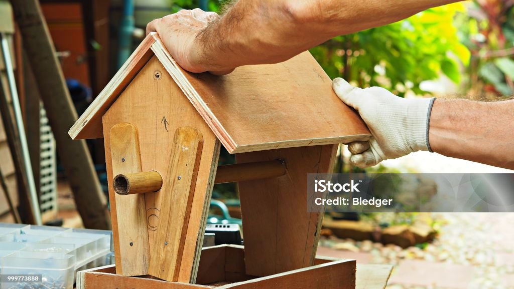 Hobbies and activities Close up on a man building wooden bird feeder in garden. Birdhouse Stock Photo