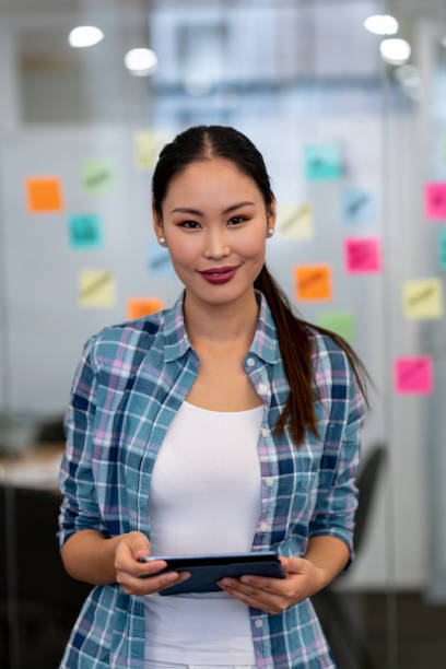 istock Asian business woman at a creative office holding a tablet computer 999790968