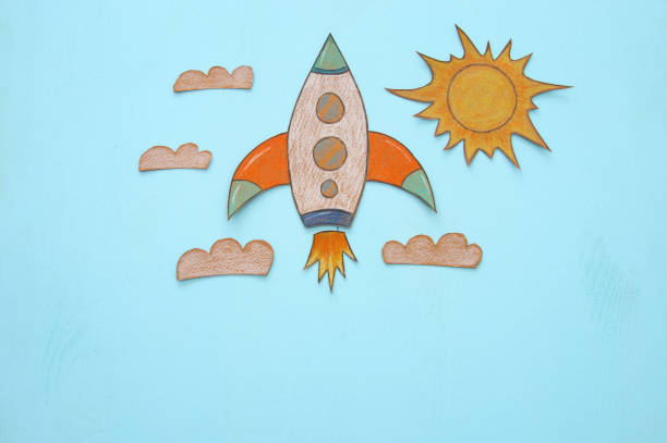 istock Rocket cut from paper and painted over wooden blue background. 999792170