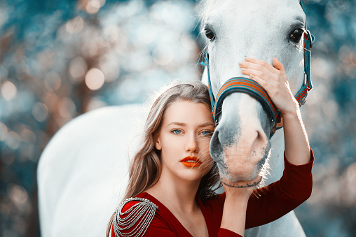 portrait of blond fashion model in nature with her horse, friendship concept.