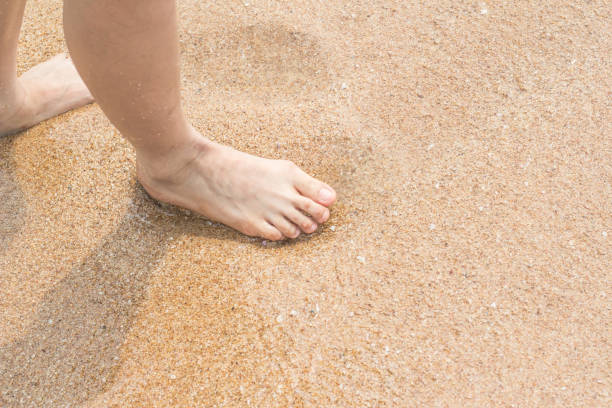 istock Woman legs walking on the beach sand 999800186