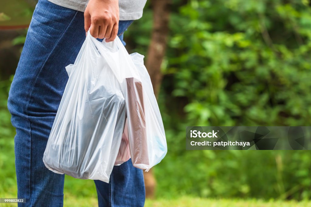 Use Plastic Bags Woman hold the plastic bags and walk on the street in the park Plastic Bag Stock Photo