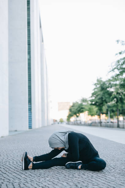 istock Female runner stretching her legs on the street 999805580
