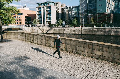 Hijab woman jogging in the city next to the Spree river.