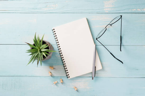istock Business, education, still life, working or planning concept : Office desk table with open notebook paper, pen and eyeglasses, Flat lay, mock up 999808002