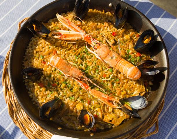 fruits de mer traditionnelle paella espagnole avec les langoustines et les moules dans une casserole - food rice lobster scampi photos et images de collection