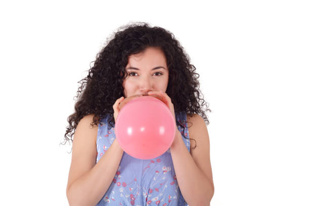 istock Young latin woman is blowing balloon. 999812090