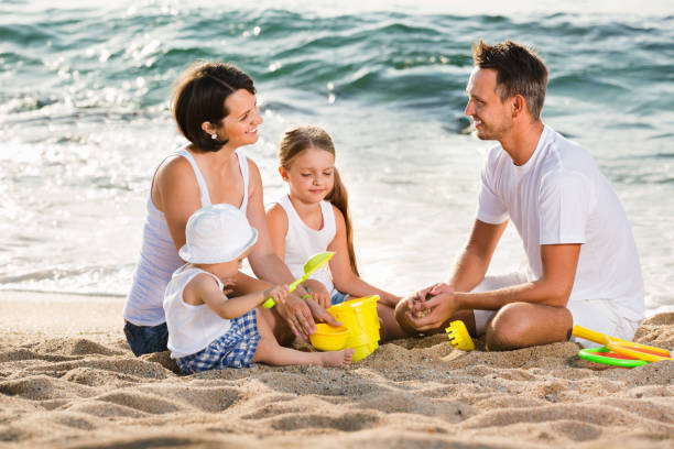 istock Parents with two kids playing with toys on beach 999812322