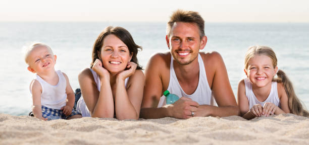 istock couple with two children lying on beach 999812380