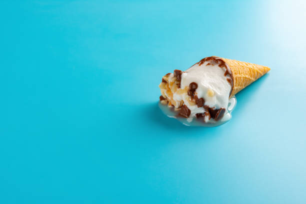 istock mini Vanilla flavor ice cream cone in a melting process on blue background 999815226