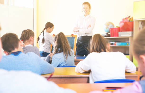 istock Schoolgirl at whiteboard with teacher 999817702