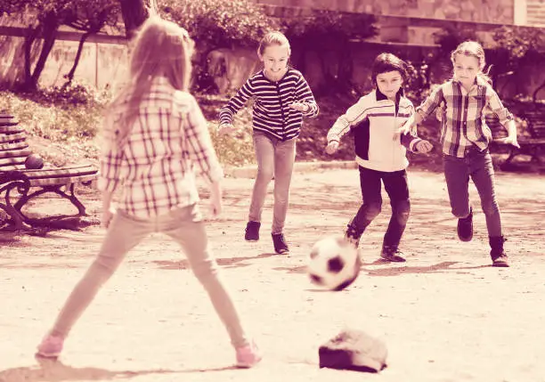 Little kids playing street football outdoors in spring day