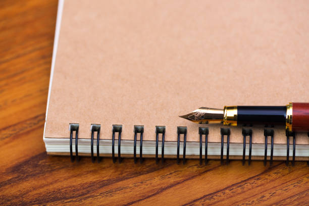 istock Fountain pen or ink pen with notebook paper on wooden working table with copy space, office desk concept. 999820944