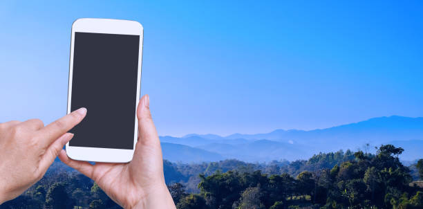 istock woman hand hold and touch screen smart phone on landscape view. 999831250