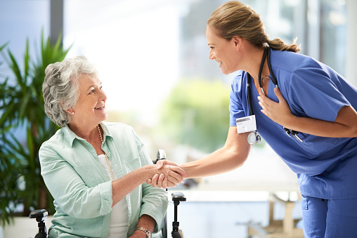 Cropped shot of an attractive female nurse shaking hands with her wheelchair-bound senior patient in the hospital