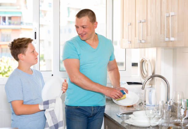istock Man with his son are washing dishes on the kitchen 999845610