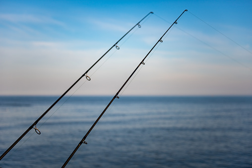 Two fishing rods with lines dropped into the North sea at Bridlington, Yorkshire.