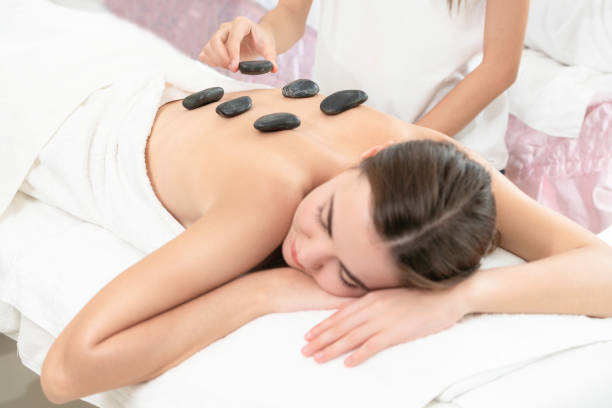 istock Hot stone massage treatment by therapist in spa. 999852184