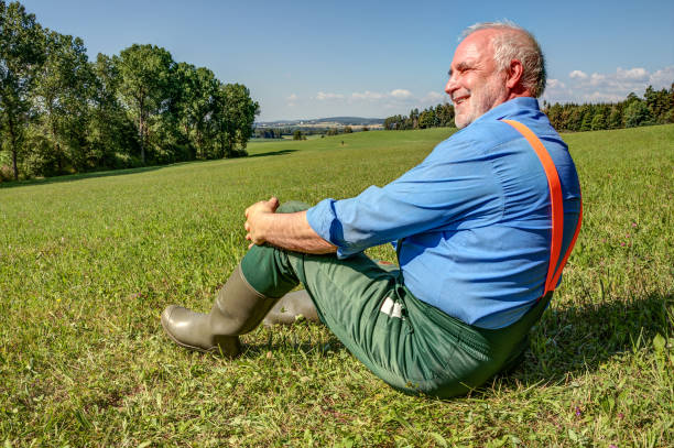 istock Farmer is sitting on his meadow and is happy. 999855584