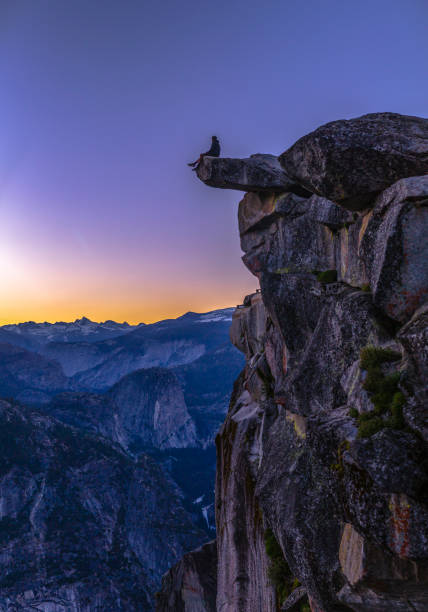 istock Man sits on the edge of a cliff at Glacier Point 999859862