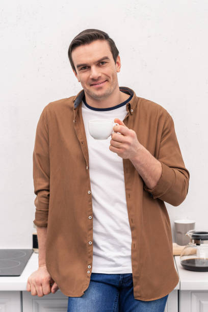 istock handsome adult man with cup of coffee on kitchen 999864886