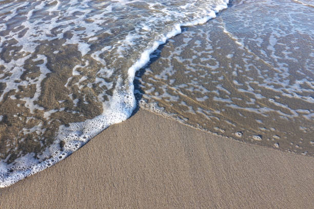 istock A soft foam wave rushes to the sandy beach. 999868368