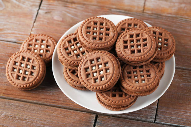 istock Chocolate cookies with cream on brown wooden table 999868410