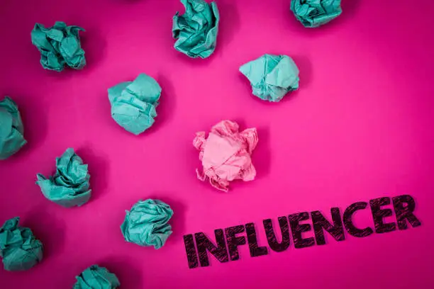 Photo of Word writing text Influencer. Business concept for Person who influences and affect decisions opinions of others Ideas messages thoughts pink background crumpled papers several tries.
