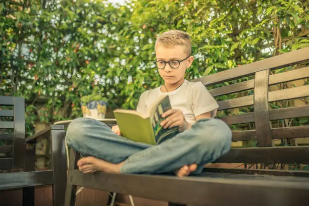 A child reading a book at home. Relax with a good book sitting outdoor barefoot