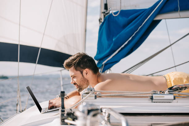 istock side view of smiling shirtless man using laptop on yacht 999880232