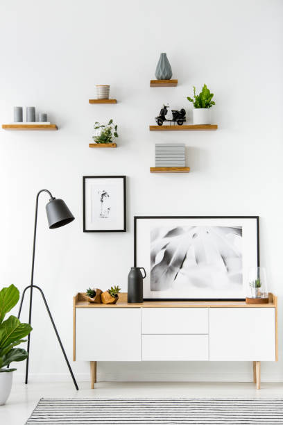 istock Black lamp next to cupboard against white wall with posters in simple flat interior. Real photo 999880494