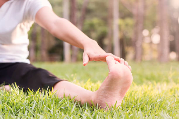 istock Woman doing stretching exercises, stretching leg (yoga) in park. 999880674