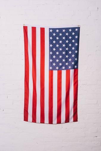 close up view of american flag hanging on white brick wall