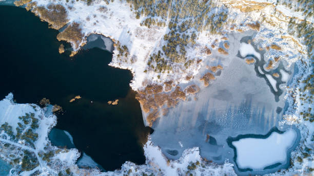Aerial photo of lake with freezing water and forest around it stock photo