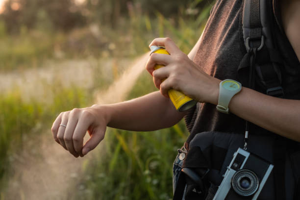 Woman using anti mosquito spray outdoors at hiking trip.