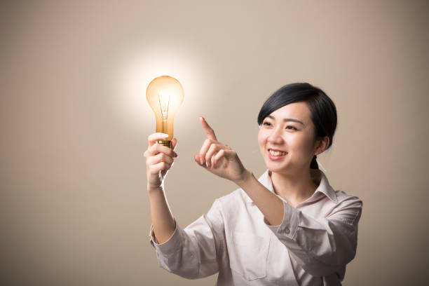 istock Young woman holding a light bulb 999892736