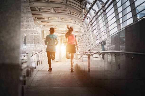 istock Beautiful two woman running over bridge during sunset. 999896306