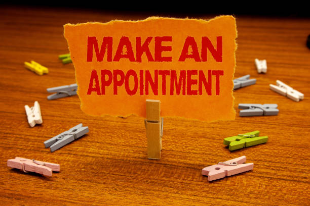 istock Writing note showing  Make An Appointment. Business photo showcasing Schedule Arrangement Deadline Session Engagement Paperclip holding orange page show red text woody floor with clip. 999899504