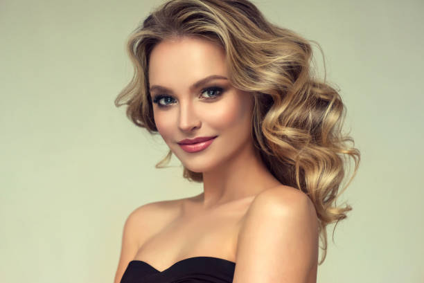 pretty blond-haired model with curly, loose hairstyle and attractive makeup. - big hair blond hair frizzy women imagens e fotografias de stock