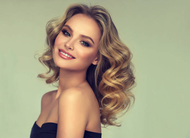 pretty blond-haired model with curly, loose hairstyle and attractive makeup. - big hair blond hair frizzy women imagens e fotografias de stock