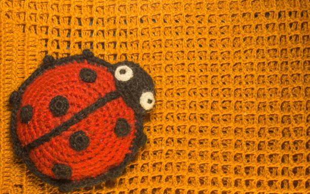 istock Knitting wool toy ladybug on the blamket colorful texture background 999934988
