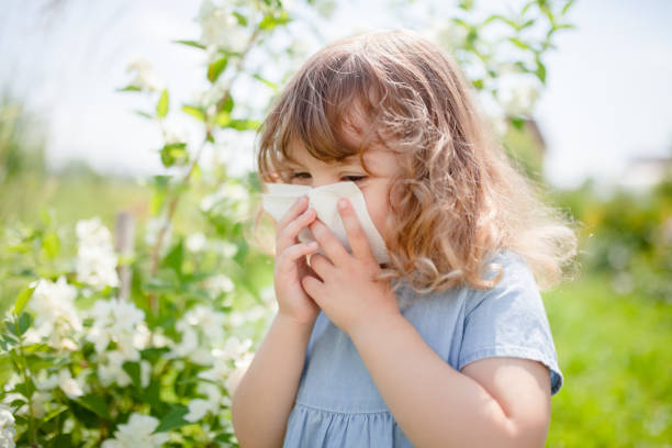 アレルギーの概念。小さな女の子が咲く木の近くの彼女の鼻を吹いています。 - 子供　アレルギー ストックフォトと画像