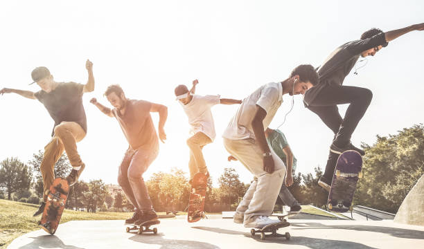 łyżwiarze skaczący z deskorolką w miejskim skate parku - młodzi faceci wykonujący triki i umiejętności na zawodach na przedmieściach zachodu słońca - sport ekstremalny i koncepcja stylu życia młodzieży - główny nacisk na mężczyznę centru - skateboarding skateboard teenager extreme sports zdjęcia i obrazy z banku zdjęć