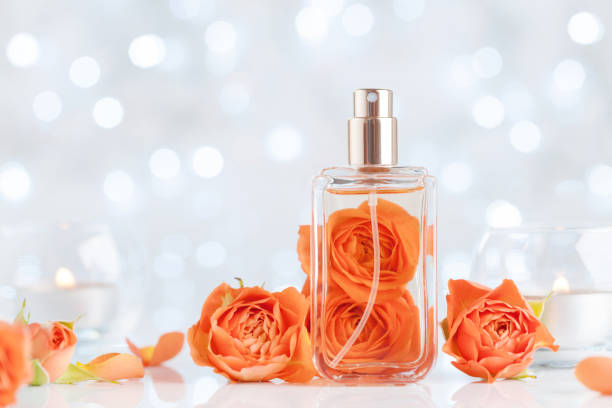 Perfume bottle and rose flowers on white table against bokeh. Beauty and perfumery background. Copy space for text.