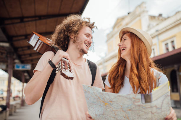 istock Smiling young couple holding a map and a guitar on a railroad station 999981004