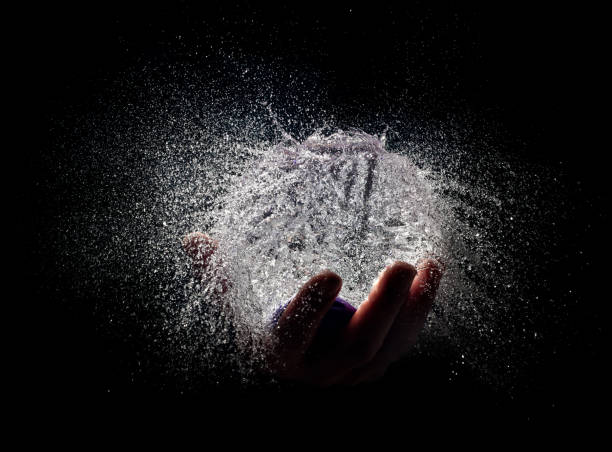 istock Cropped Hand Splashing Water Against Black Background 999984626